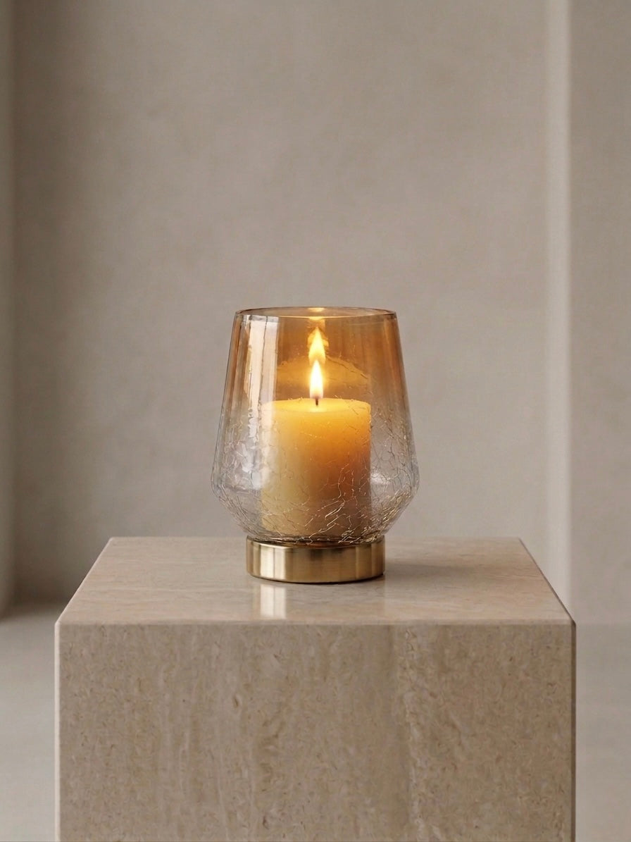 Candle in a glass holder on a beige pedestal against a neutral wall